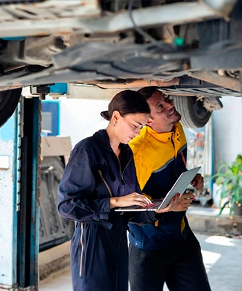 Mujer y hombre revisando carrocería de un carro en fabricación