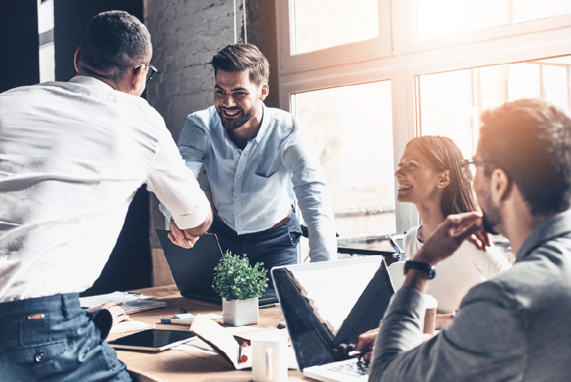 Business meeting with four smiling people in an office.